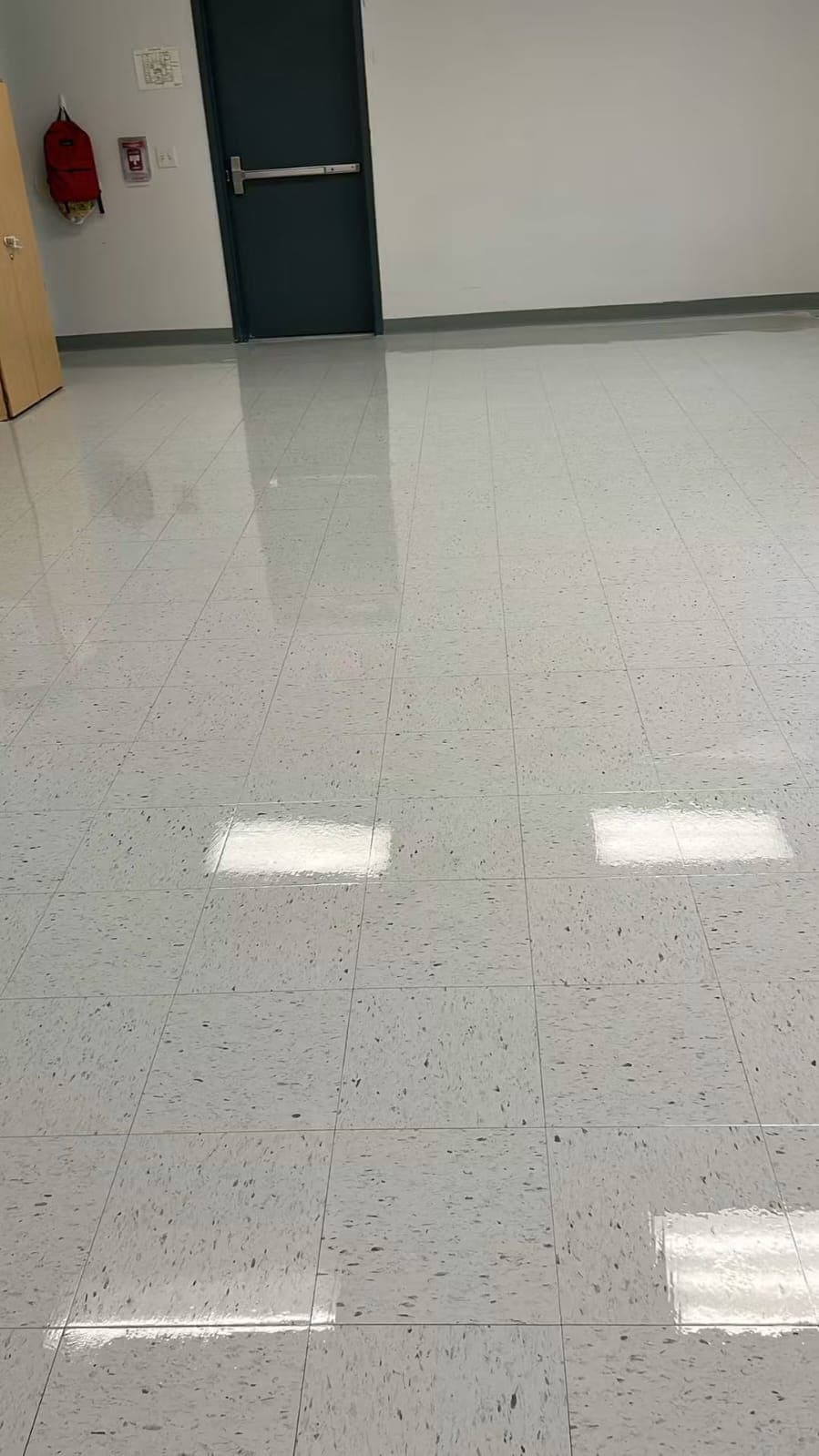 A freshly stripped and waxed VCT floor with a high-gloss finish in an institutional building